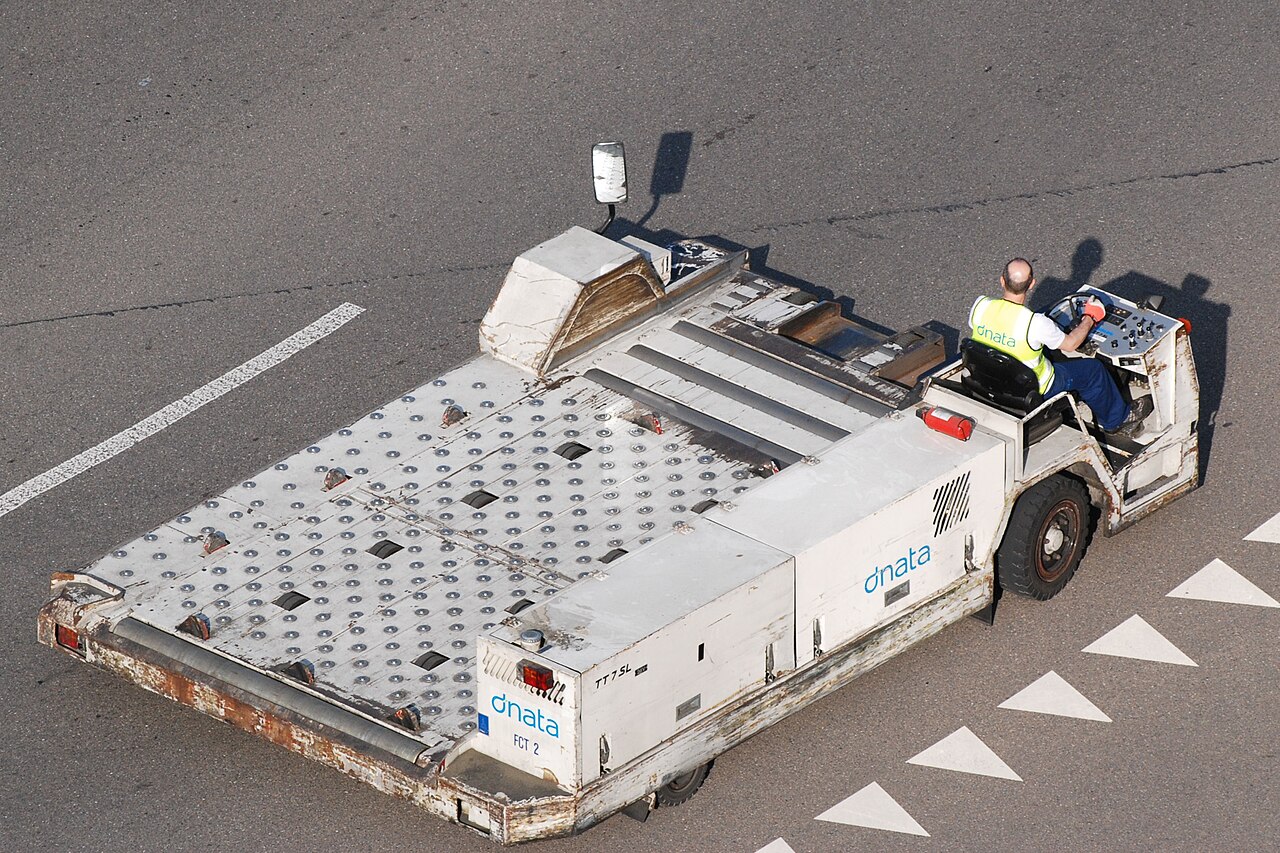Ground crew operating a cargo loader beside an aircraft